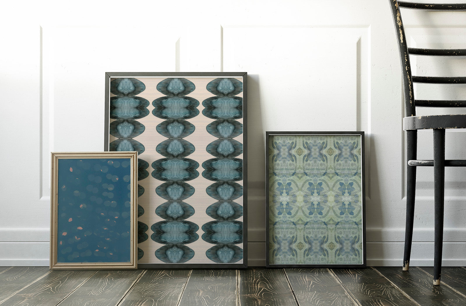 Three framed art prints sitting on a wooden floor.