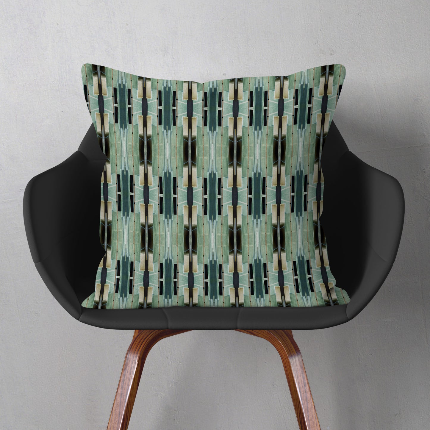 Throw pillow featuring an abstract geometric green pattern sitting on a gray chair