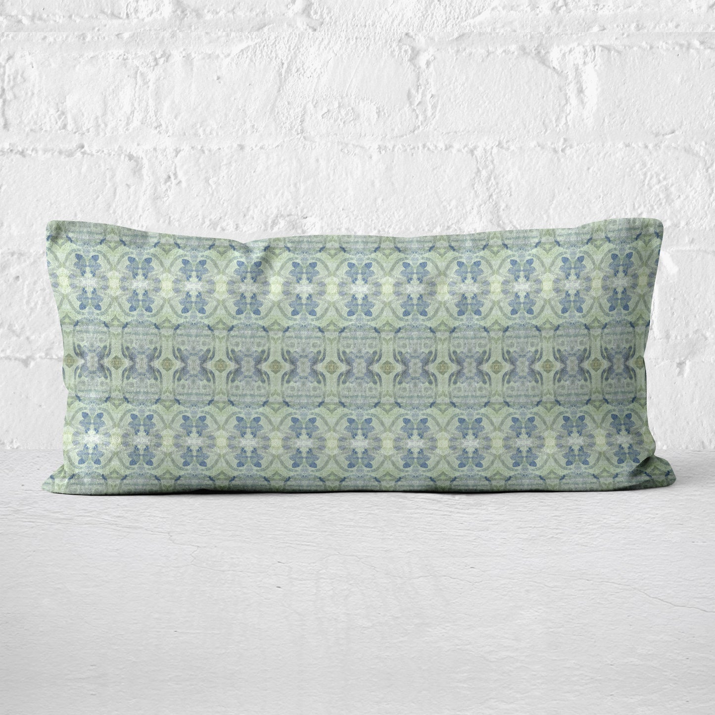 Lumbar pillow featuring an abstract blue and green floral pattern leaning against a white brick wall