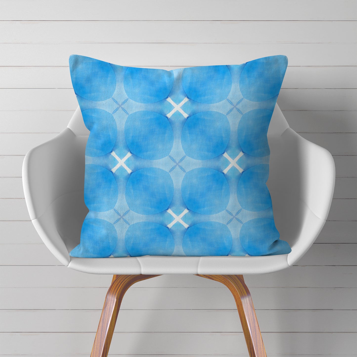 Square throw pillow with blue circular pattern on white chair