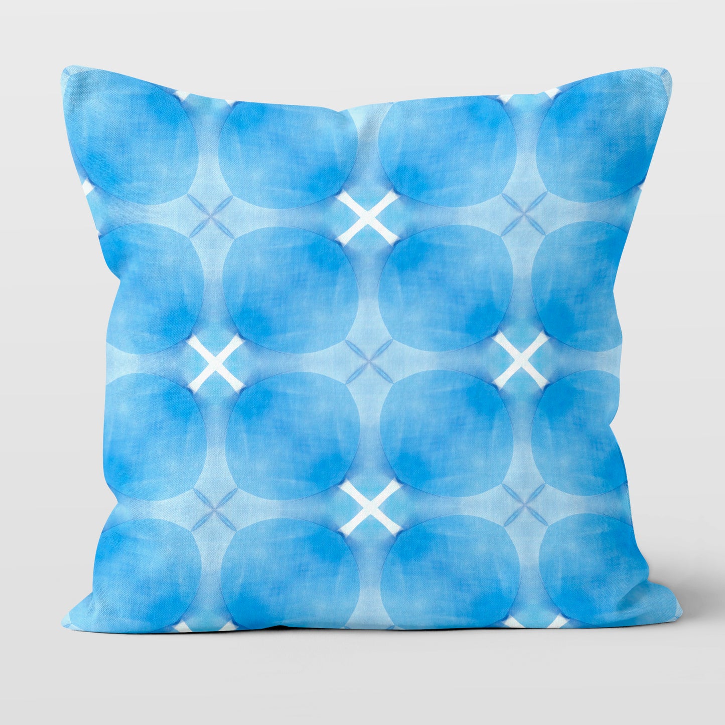 Square throw pillow with blue circular pattern on white background