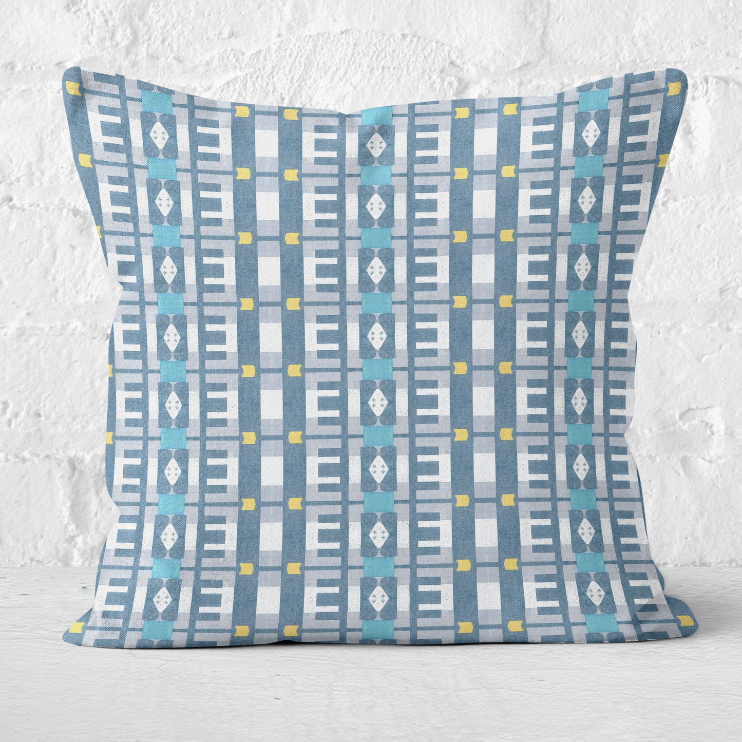 Throw pillow featuring a geometric blue and white pattern against a white brick background