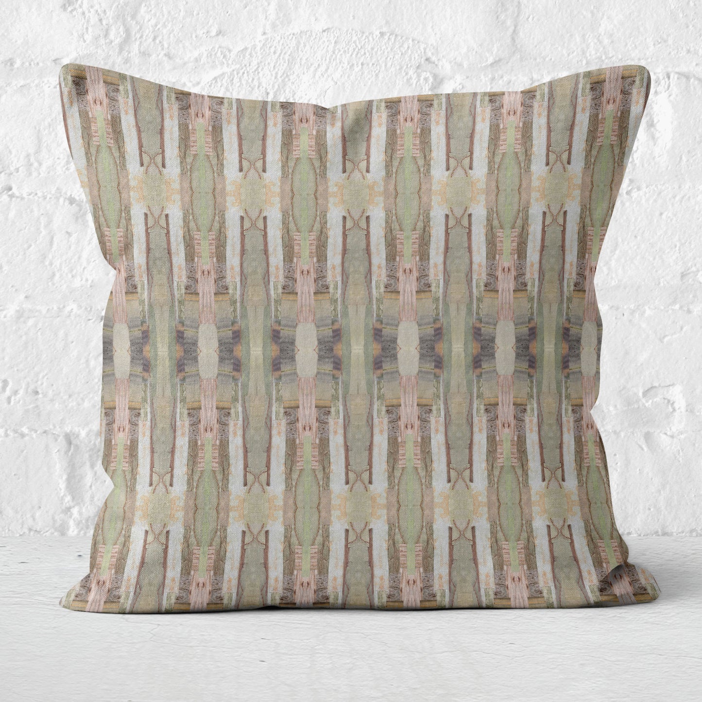 Throw pillow featuring muted pink and green collaged pattern against a white brick background