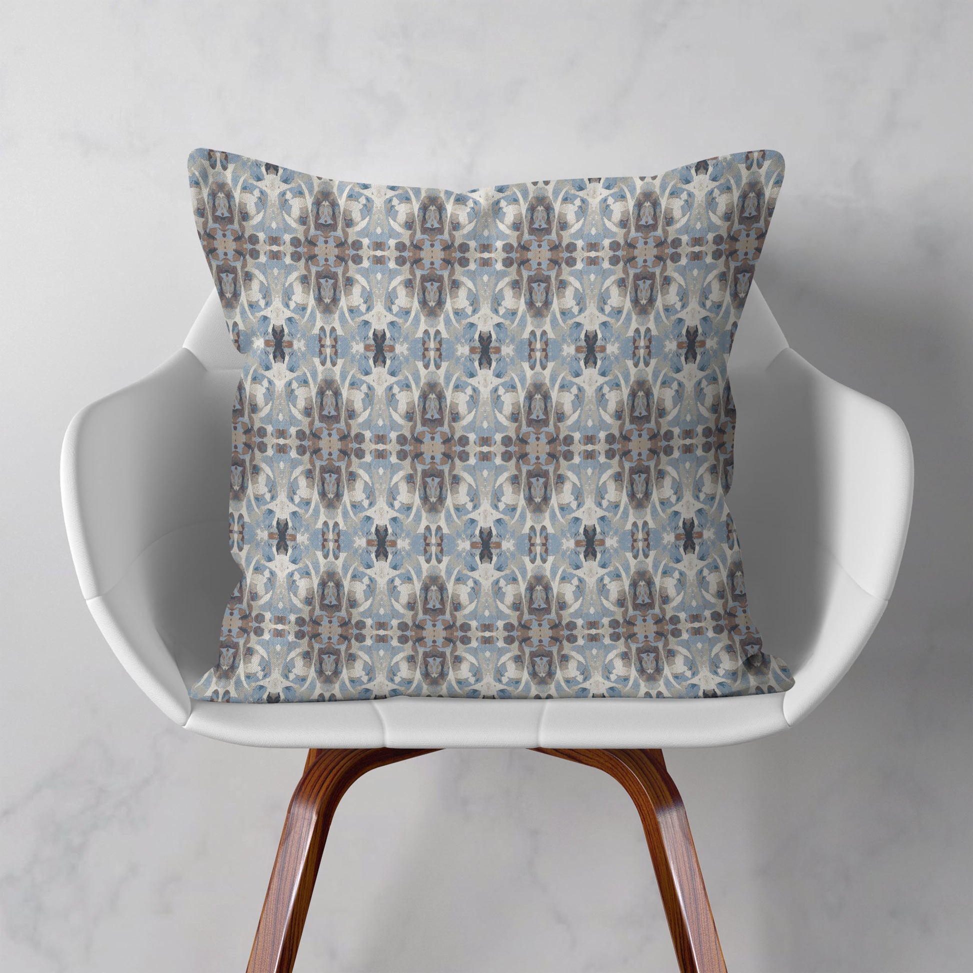 Blue and brown patterned pillow sitting on a modern white chair
