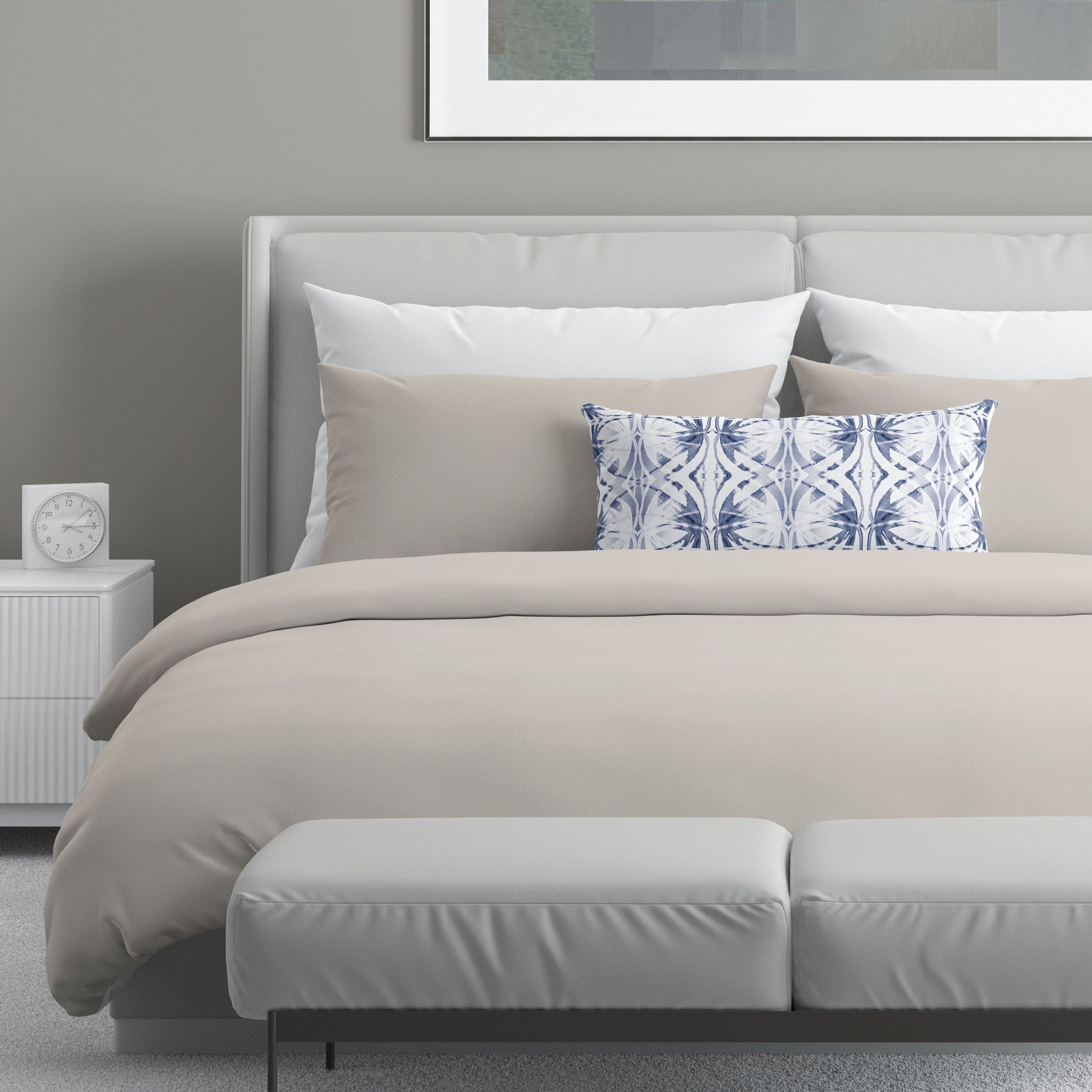Neutral colored bedroom featuring a bed with a blue and white abstract patterned lumbar pillow.