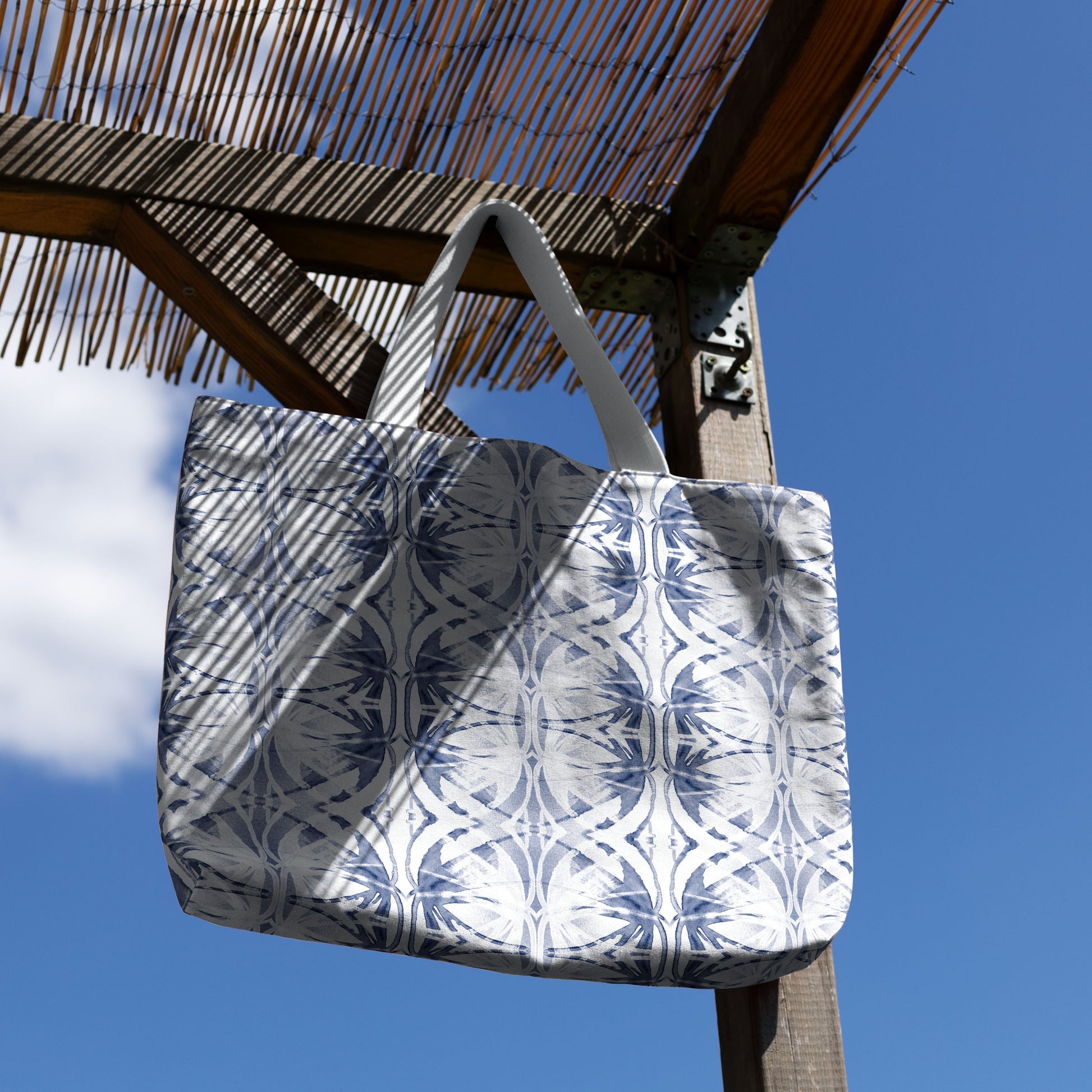 Blue and white pattern tote bag hanging from a thatched wood canopy