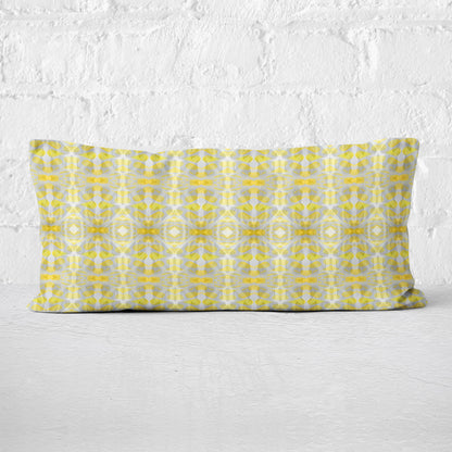 Rectangular lumbar pillow featuring handprinted striped yellow and grey pattern leaning against a white brick wall.
