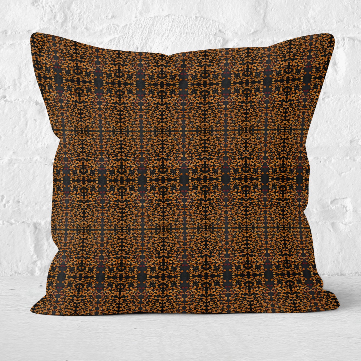 Square throw pillow featuring a hand-pattern in black and copper tones with white brick wall in background
