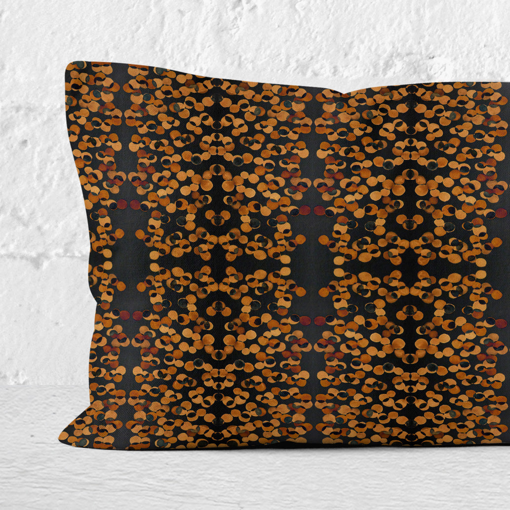Detail of a rectangular lumbar pillow featuring a hand-painted black and copper tone pattern.