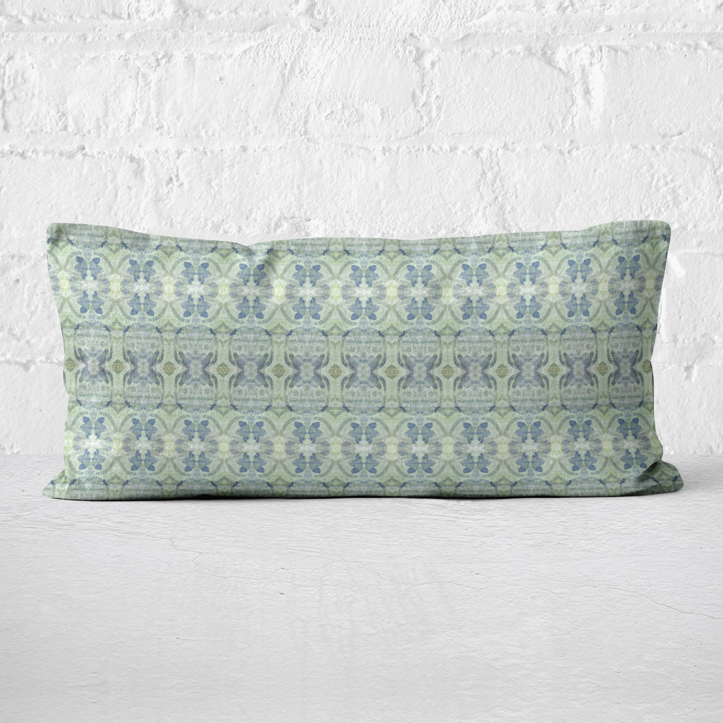 Lumbar pillow featuring an abstract blue and green floral pattern leaning against a white brick wall