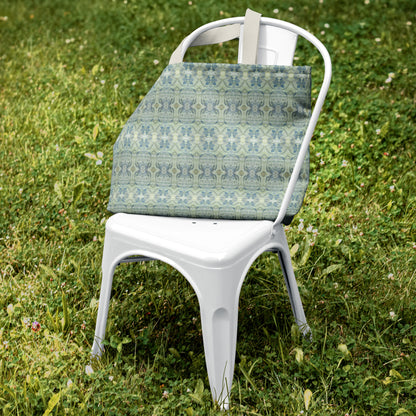 Canvas tote bag featuring an abstract blue and green pattern sitting on a white metal chair in green grass