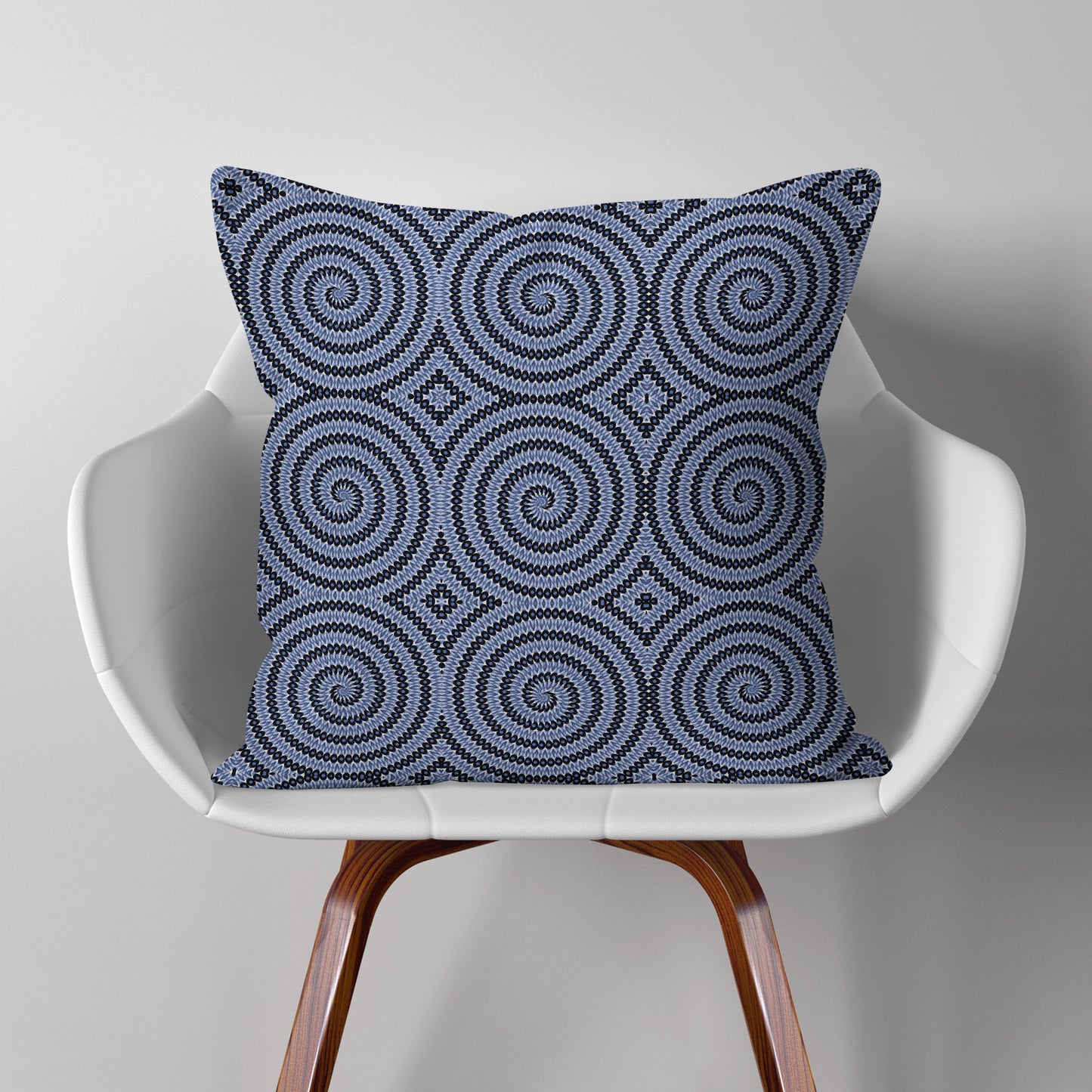 Pillow featuring geometric circular pattern in blue and white, sitting on a modern white chair