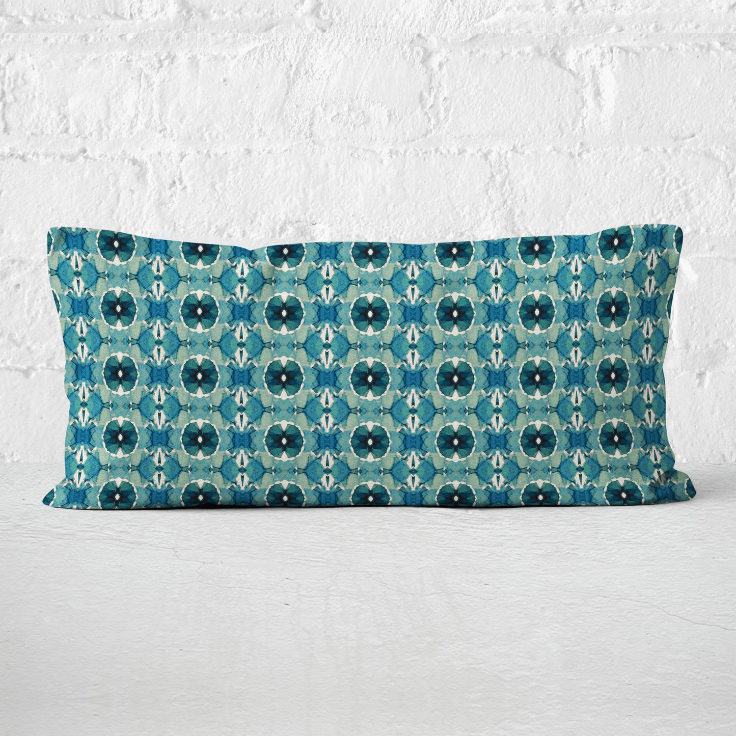 12 x 24 lumbar pillow featuring an abstract hand-painted teal pattern set against a white brick wall.