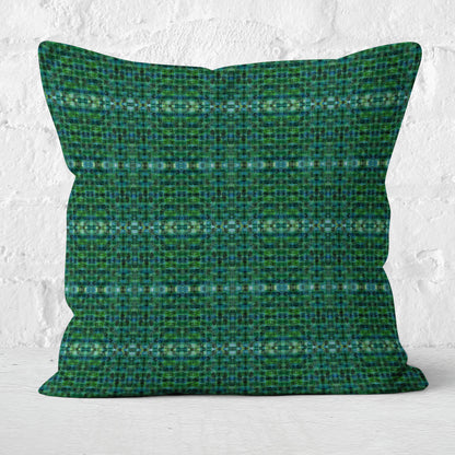 Square pillow featuring a green plaid pattern sitting in front of a white brick wall