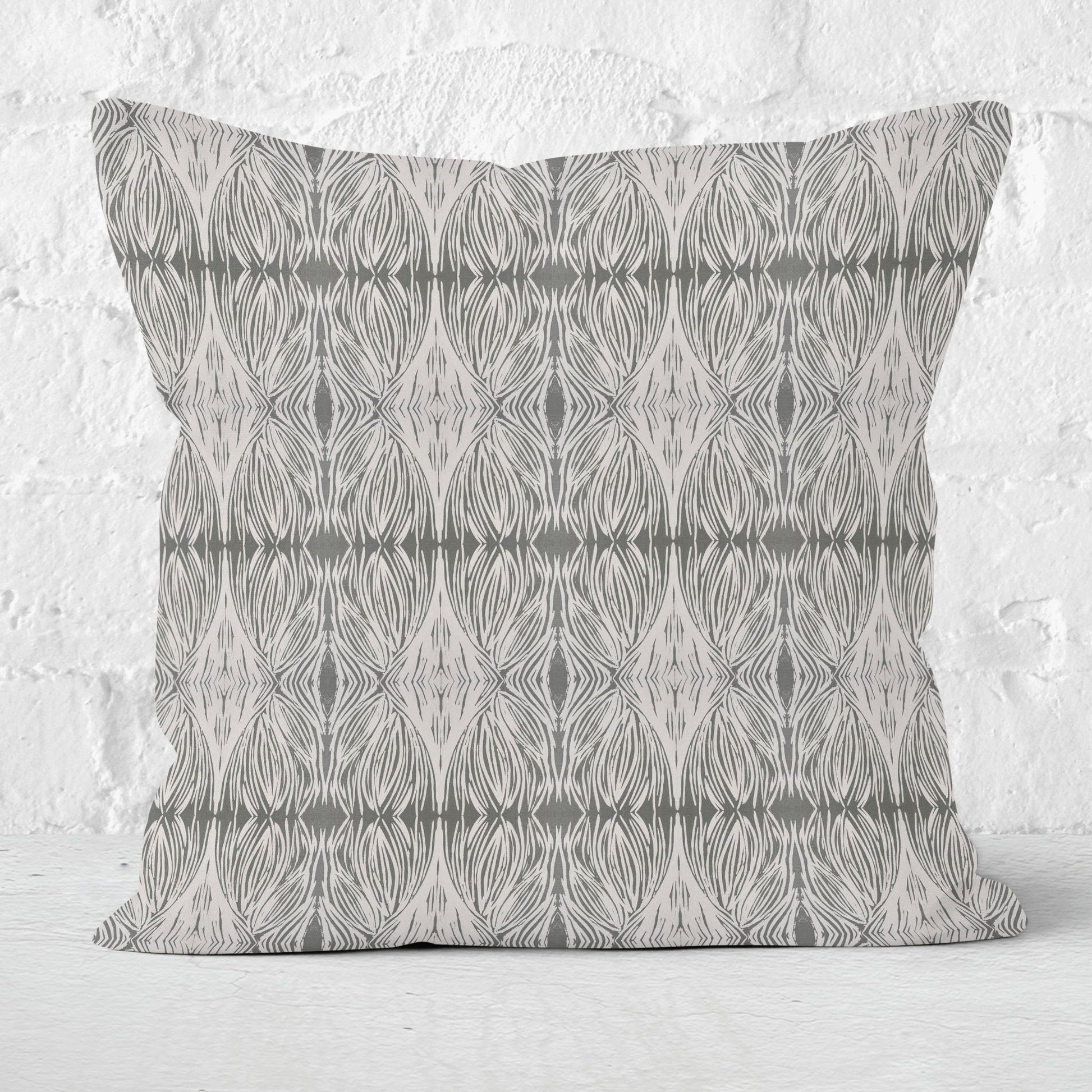Square throw pillow featuring an abstract linocut pattern in grey with a white brick wall in the background