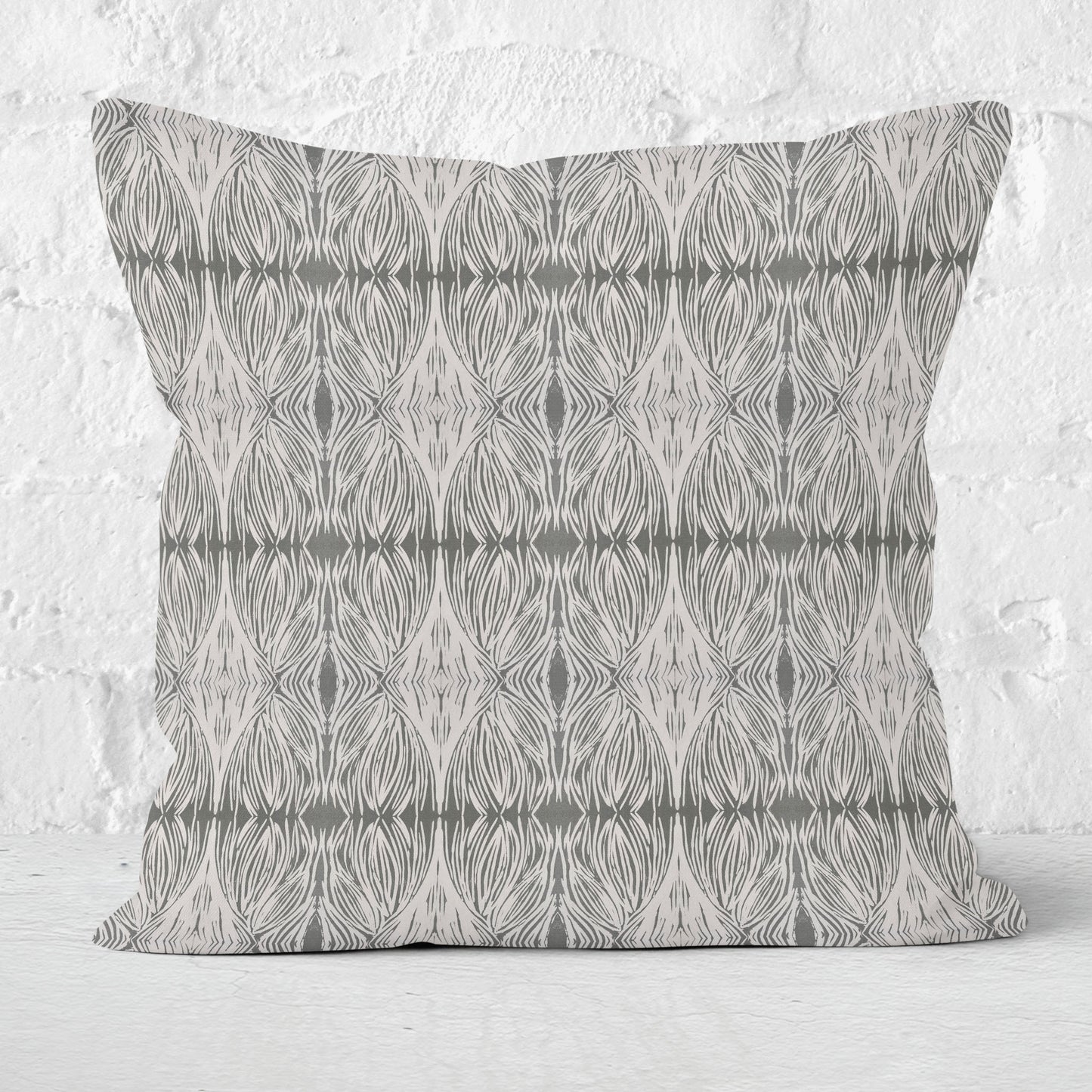 Square throw pillow featuring an abstract linocut pattern in grey with a white brick wall in the background