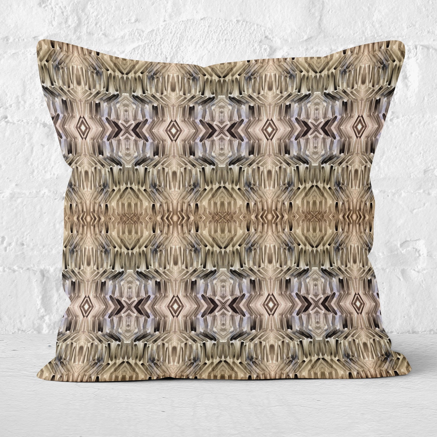 Pillow featuring abstract hand-painted pattern in neutral tones with white brick wall in background