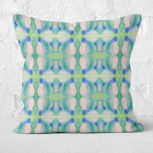Square throw pillow featuring a blue and green abstract watercolor pattern against a white brick background