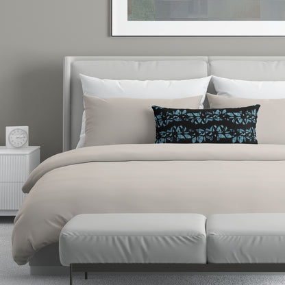 Neutral colored bedroom featuring a bed with a black and teal abstract patterned lumbar pillow.