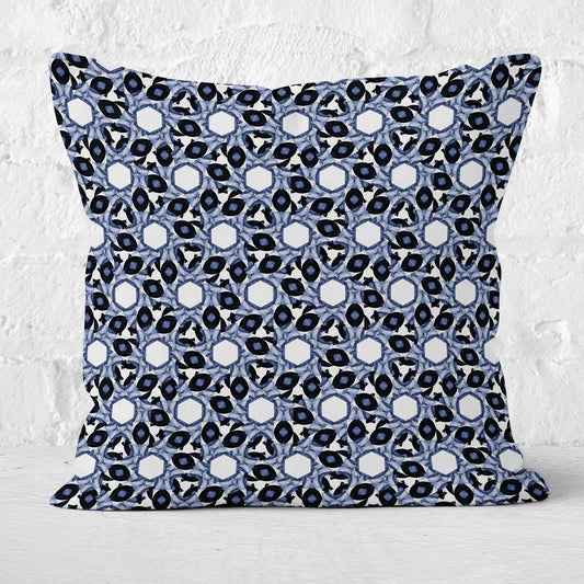 Throw pillow featuring abstract geometric blue and white pattern with a white brick wall in the background