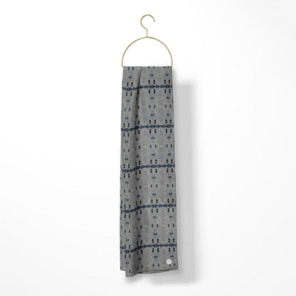 Oblong scarf with a gray abstract pattern hanging from a gold hanger