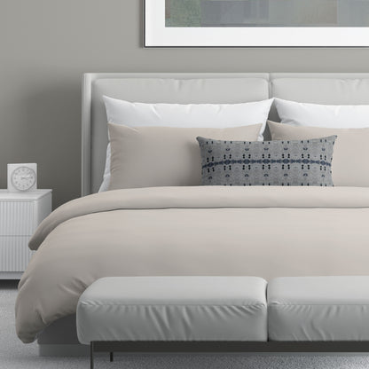 Neutral colored bedroom featuring a bed with a gray and blue abstract patterned lumbar pillow.