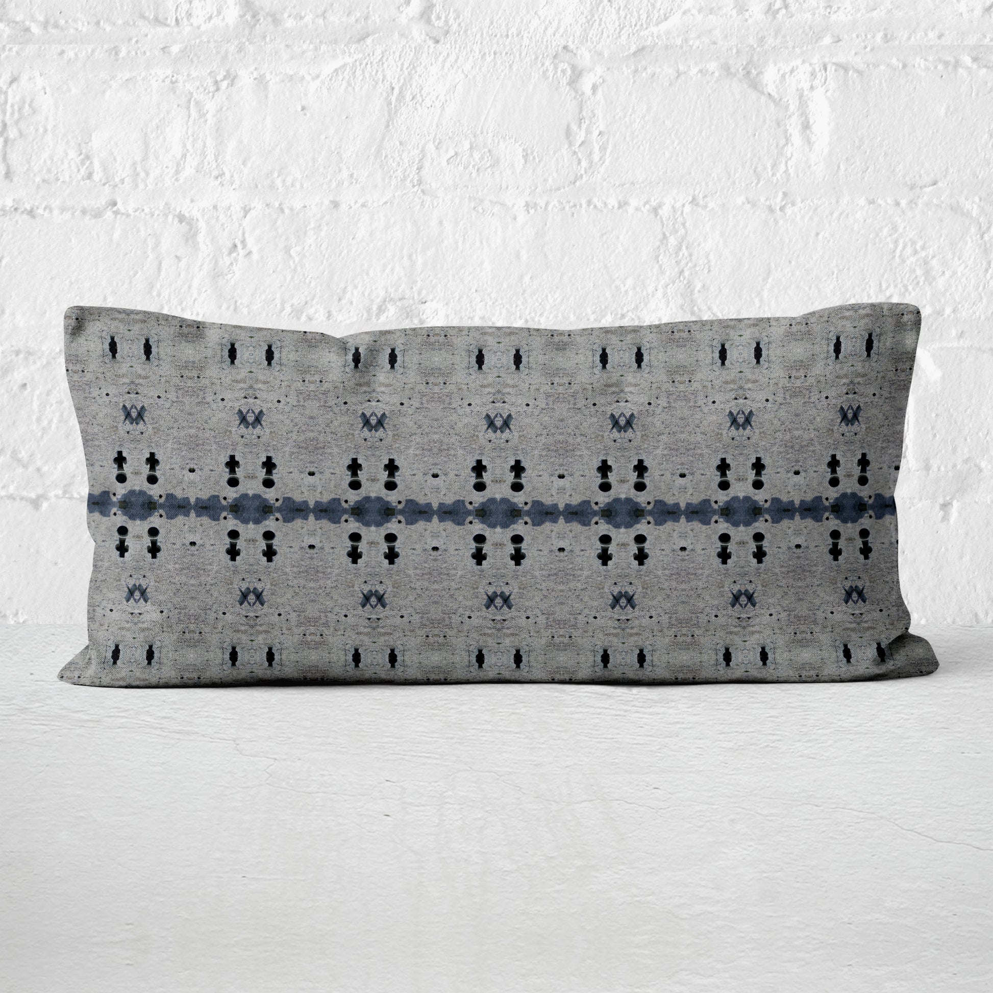 12x24 rectangular lumbar pillow featuring an abstract gray and dark blue pattern, set against a white wall