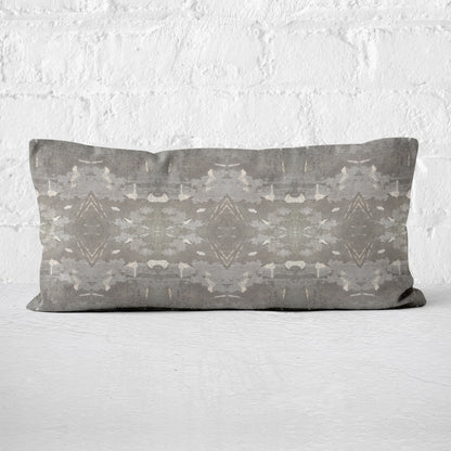Lumbar pillow featuring a grey abstract geometric pattern leaning against a white brick wall