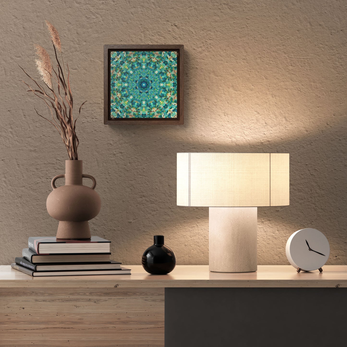 Stretched canvas featuring a teal abstract pattern in a brown float frame hanging over a desk with a vase and lamp