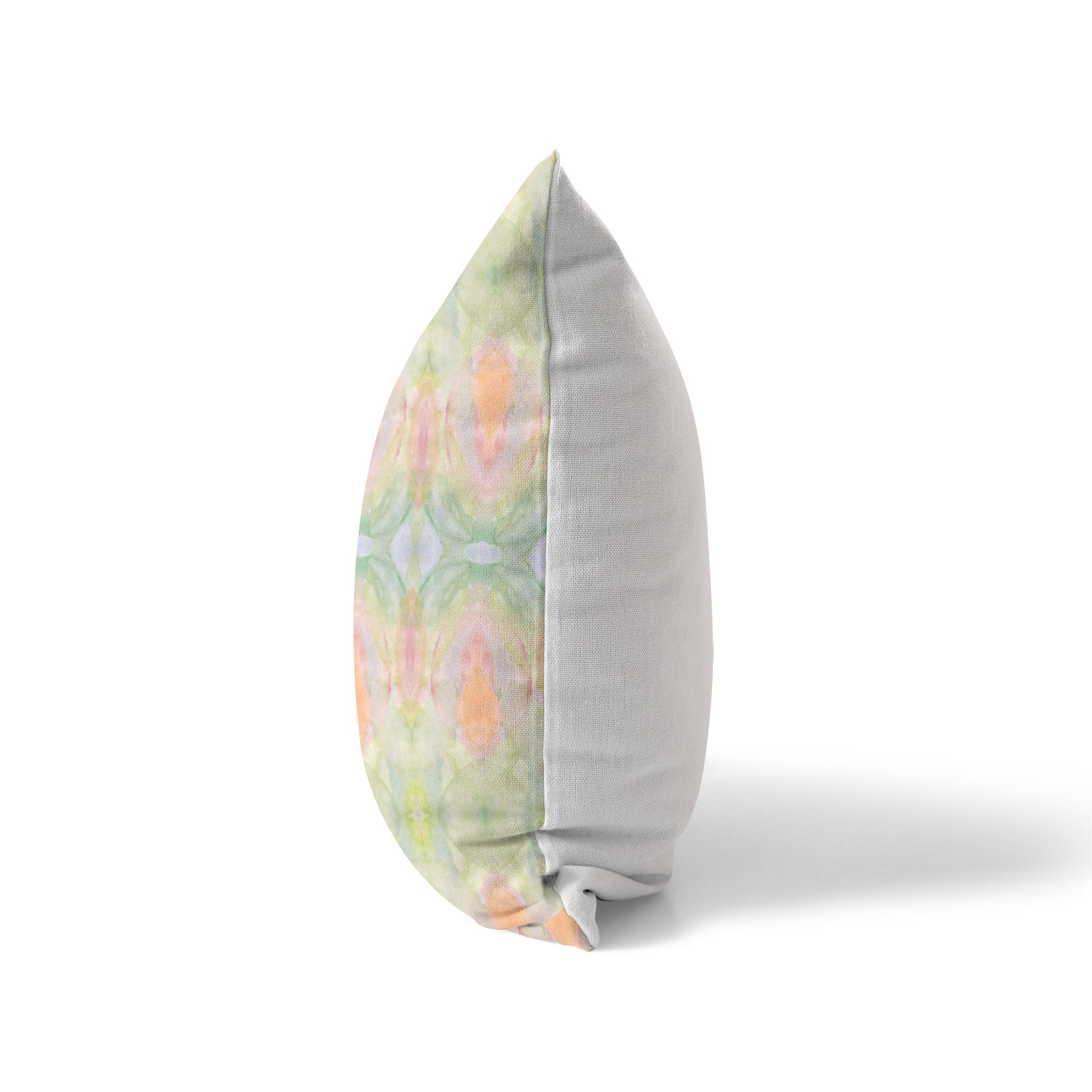 Side view of a pillow featuring a peach and green abstract pattern and solid white back