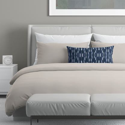 Neutral colored bedroom featuring a bed with a navy blue abstract patterned lumbar pillow.