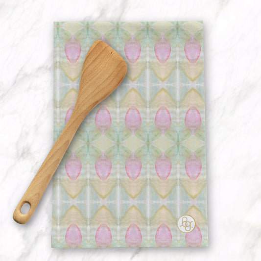 Folded tea towel featuring an abstract pink floral pattern with a wooden spoon