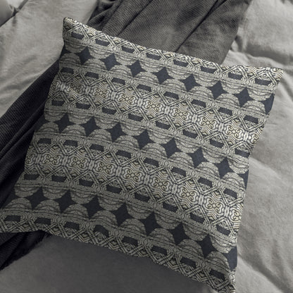 Black and gray abstract patterned pillow lying against a gray blanket