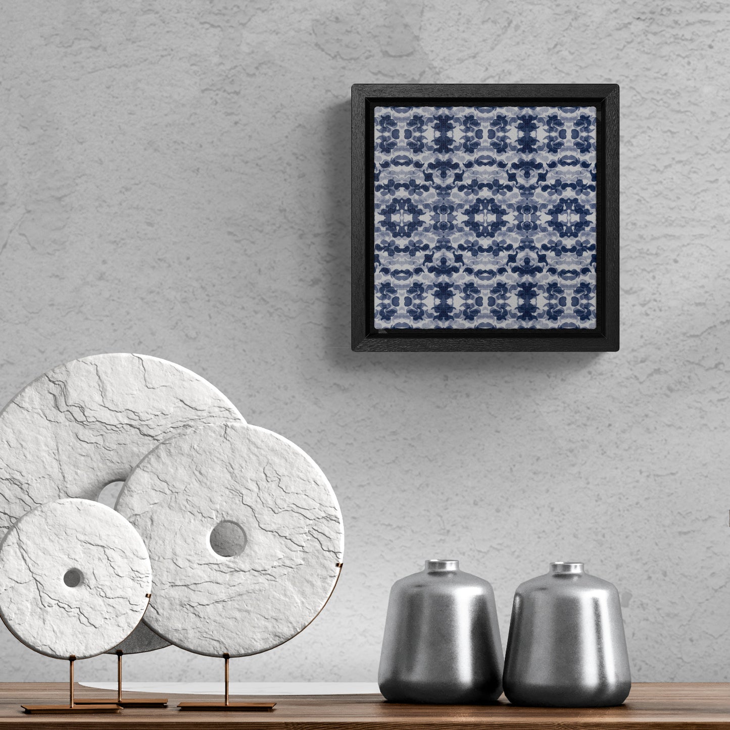 Smalled framed canvas featuring a navy blue paisley pattern hanging above a table with small sculptures
