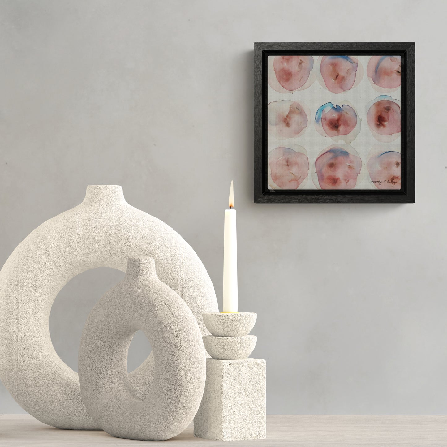 Framed canvas print featuring abstract circles in pink and blue, hanging over a collection of white vases