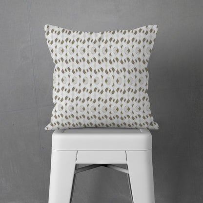 Square throw pillow featuring a painterly abstract pattern in off-white, tan, and gray, sitting on a white metal stool.