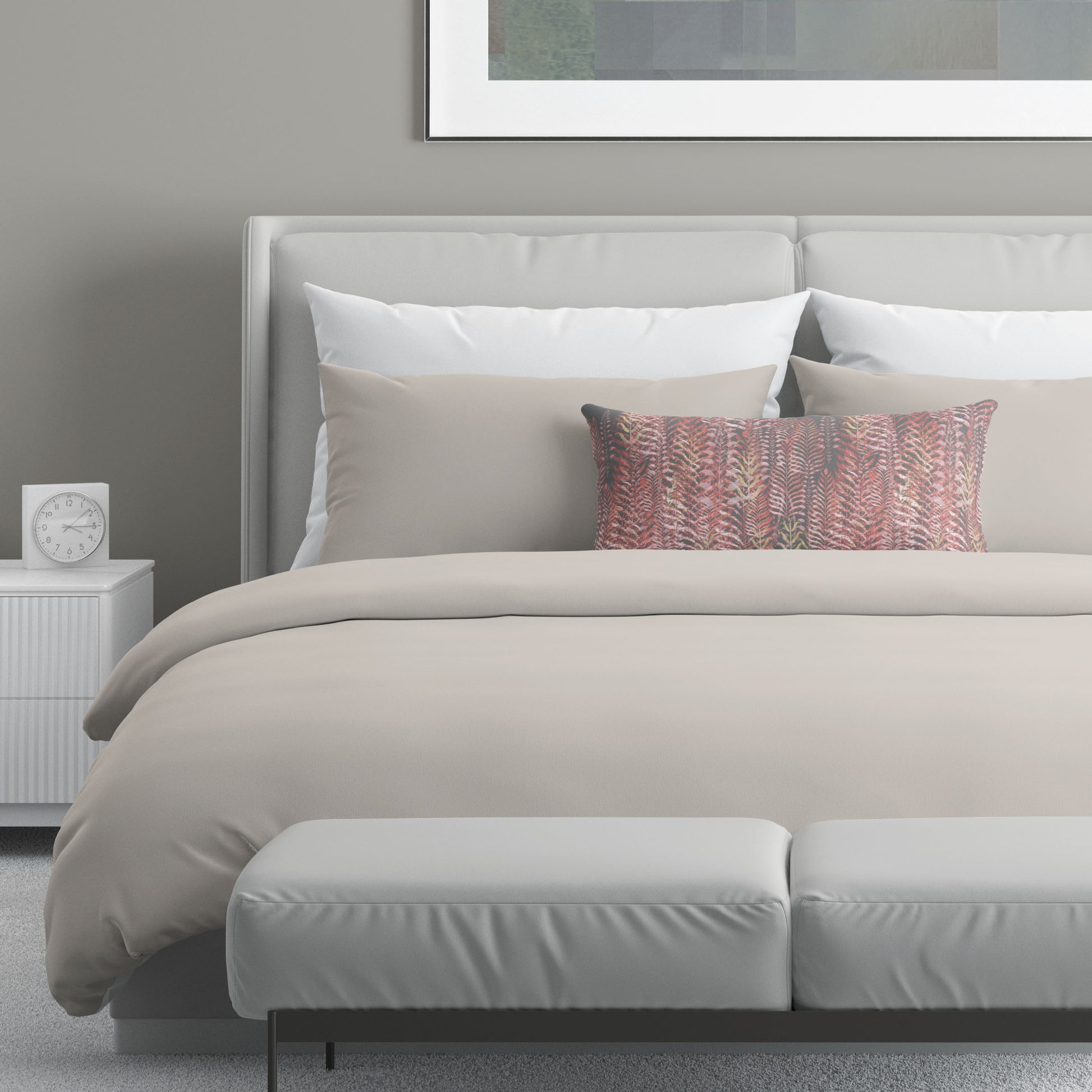 12 x 24 inch lumbar pillow featuring feather block print in pink and gray tones on top of neutral bed linens.