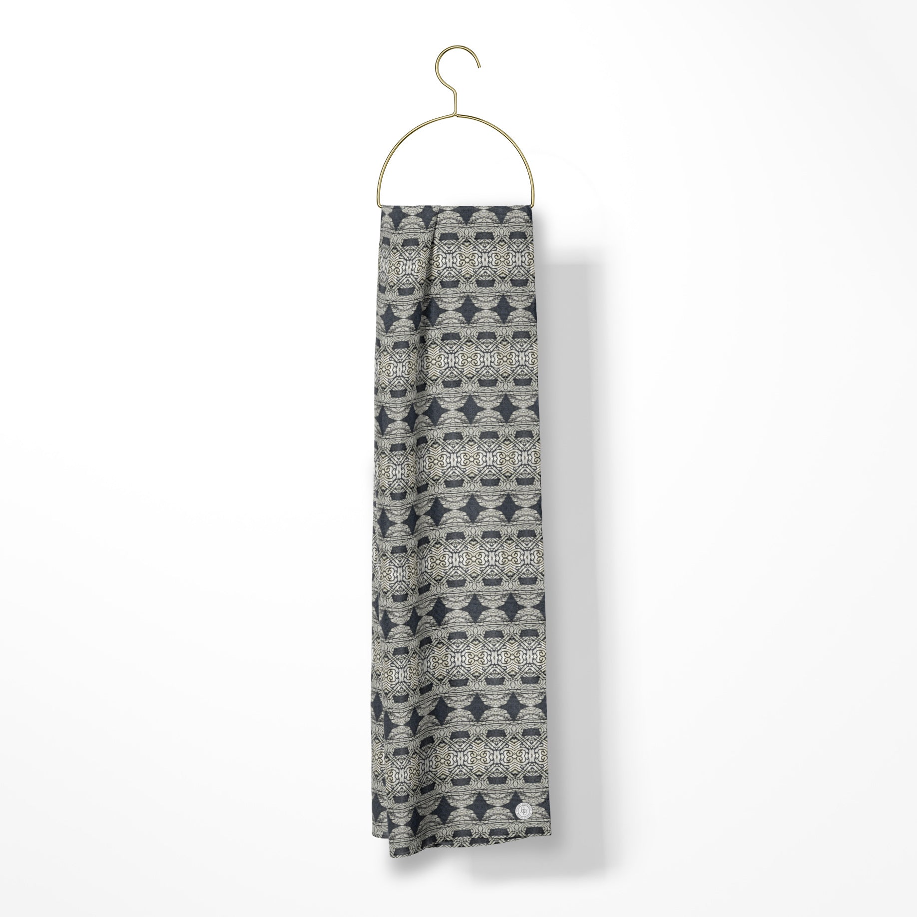 Oblong silk scarf featuring a charcoal gray abstract pattern, draped over a gold hanger