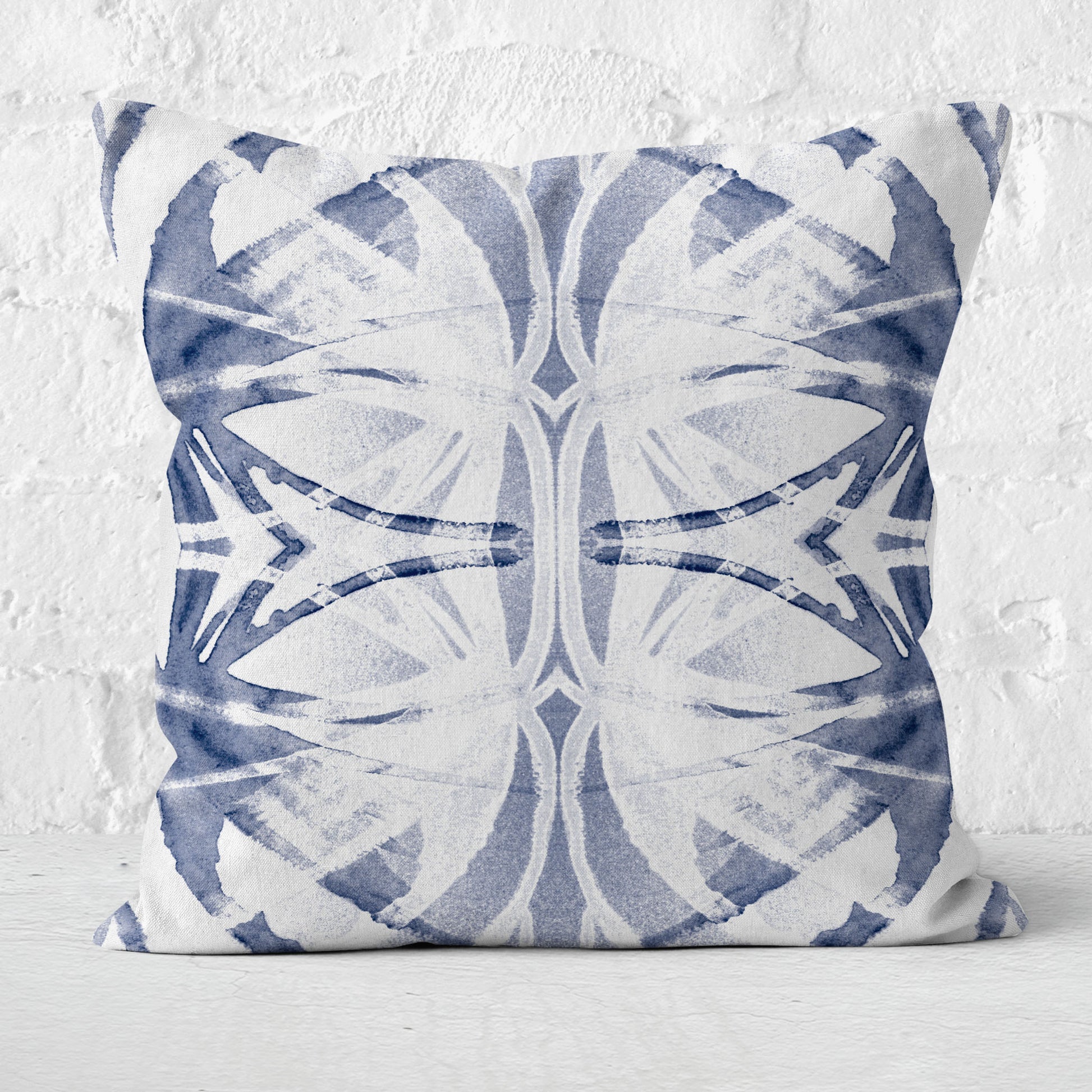 Throw pillow featuring an abstract blue watercolor pattern on a white brick background