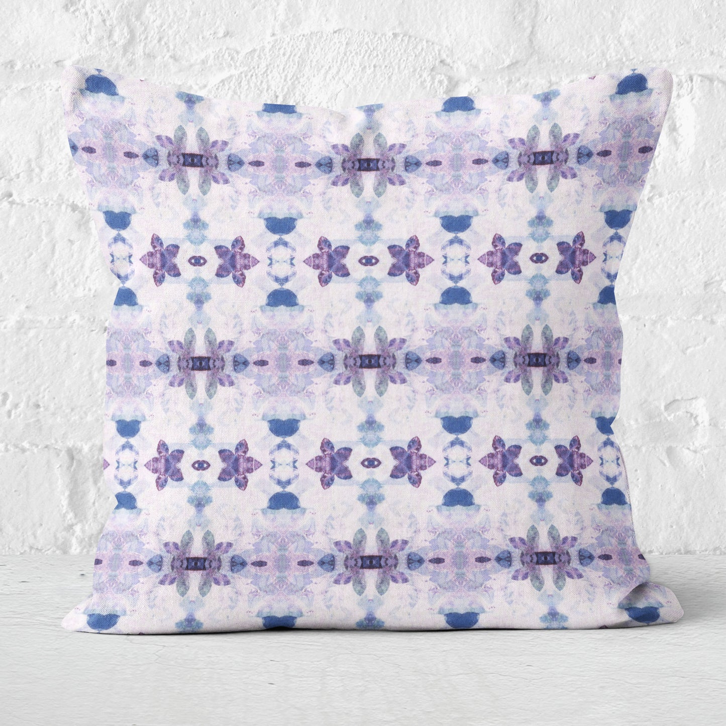 Square throw pillow featuring a purple and blue floral pattern on a white brick background