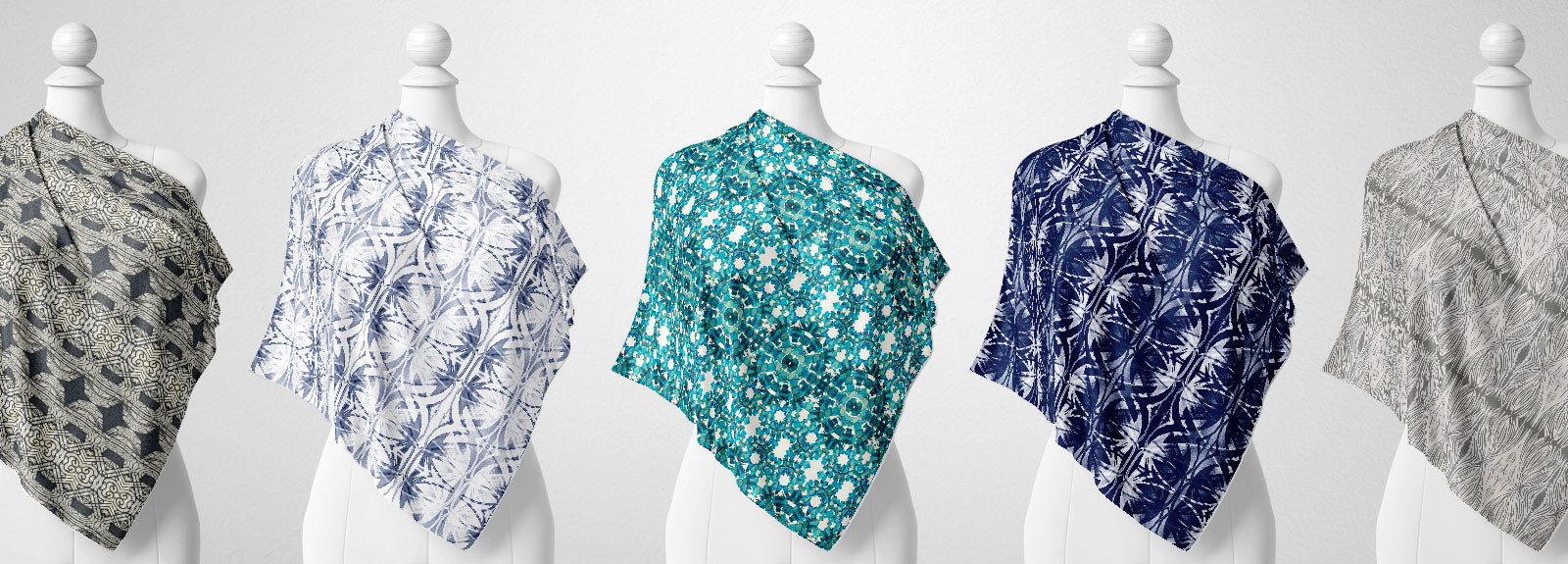 Row of mannequins wearing silk scarves, featuring blue and gray hand-painted patterns.