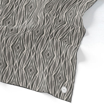 Image detail of a silk scarf featuring a linocut pattern in beige, gray, and black.