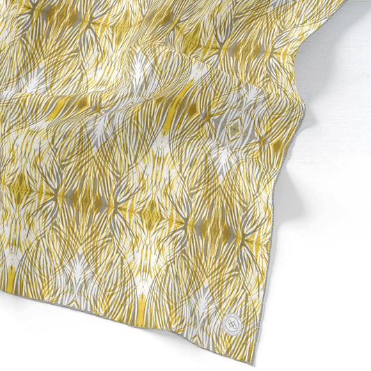 Silk scarf featuring a linocut print pattern in gold and gray.