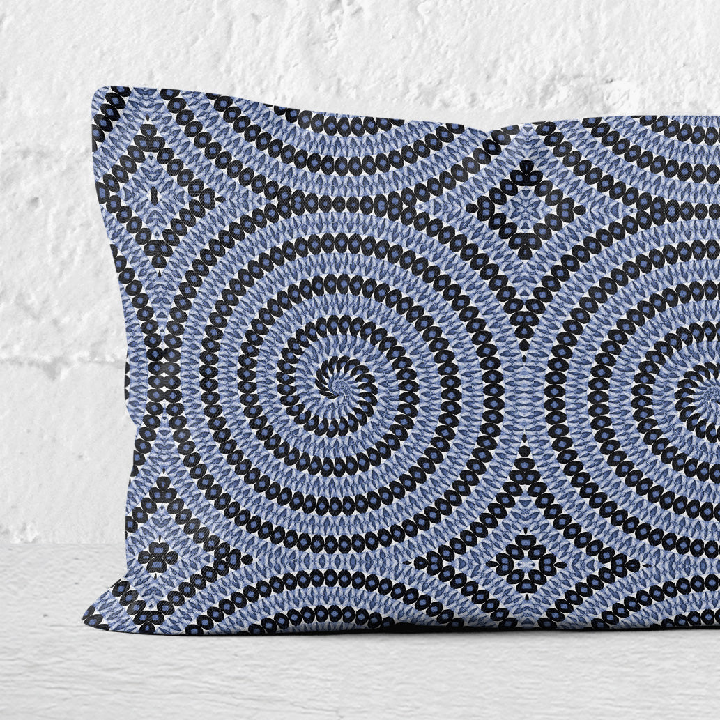 Detail of a rectangular lumbar pillow featuring hand-painted and collaged blue and white spiral pattern.