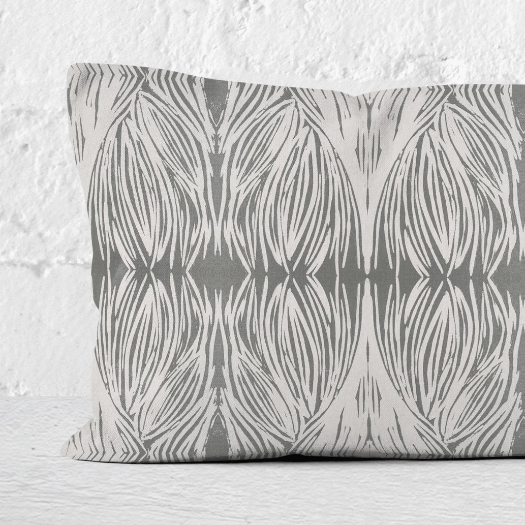 Detail of a rectangular lumbar pillow featuring an abstract linocut pattern in grey tones.