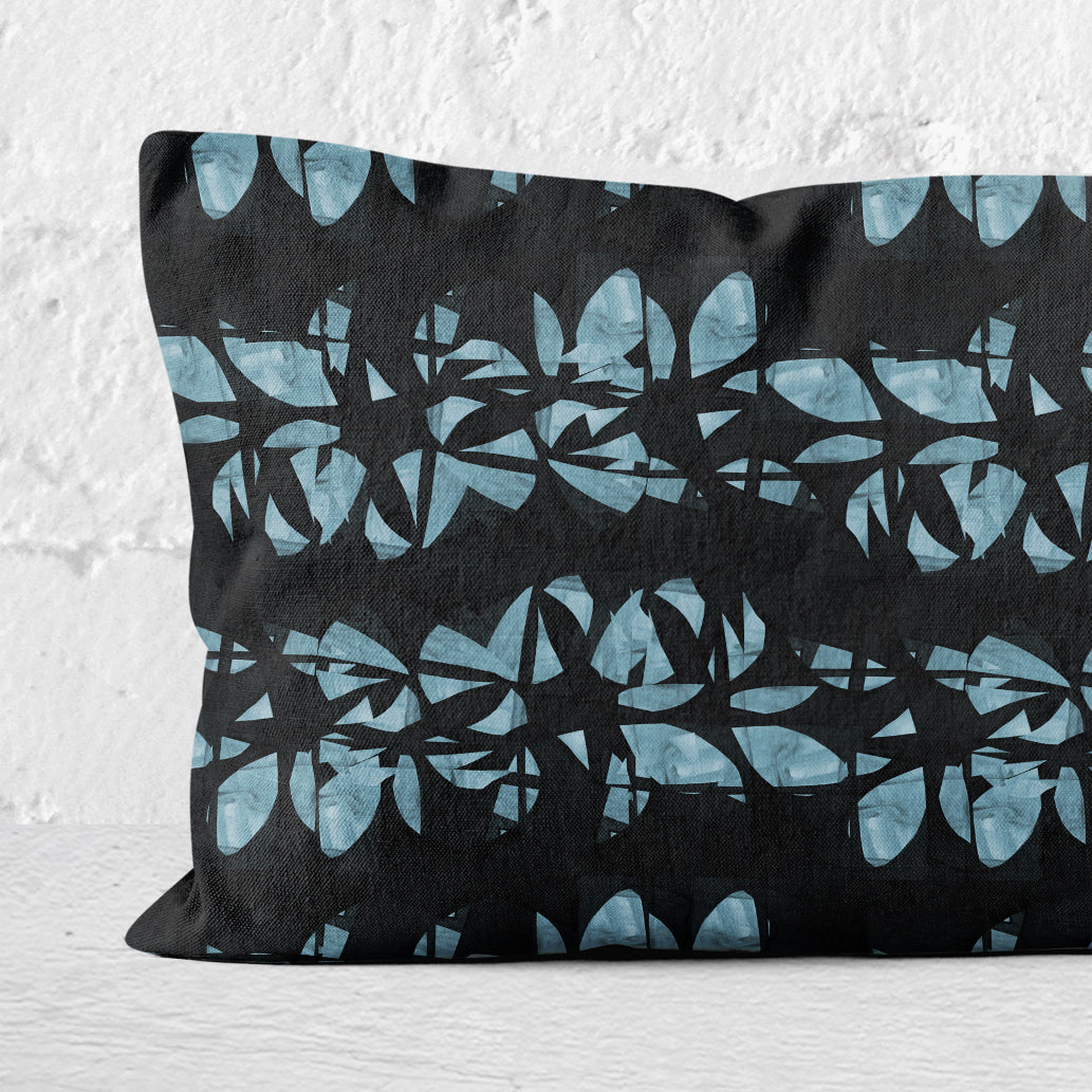 Lumbar pillow featuring an abstract black and aqua floral lei pattern