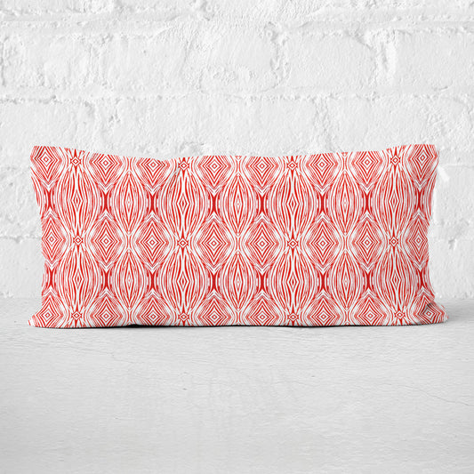 12 x 24 lumbar pillow featuring a red and white abstract linocut pattern leaning against a white brick wall.