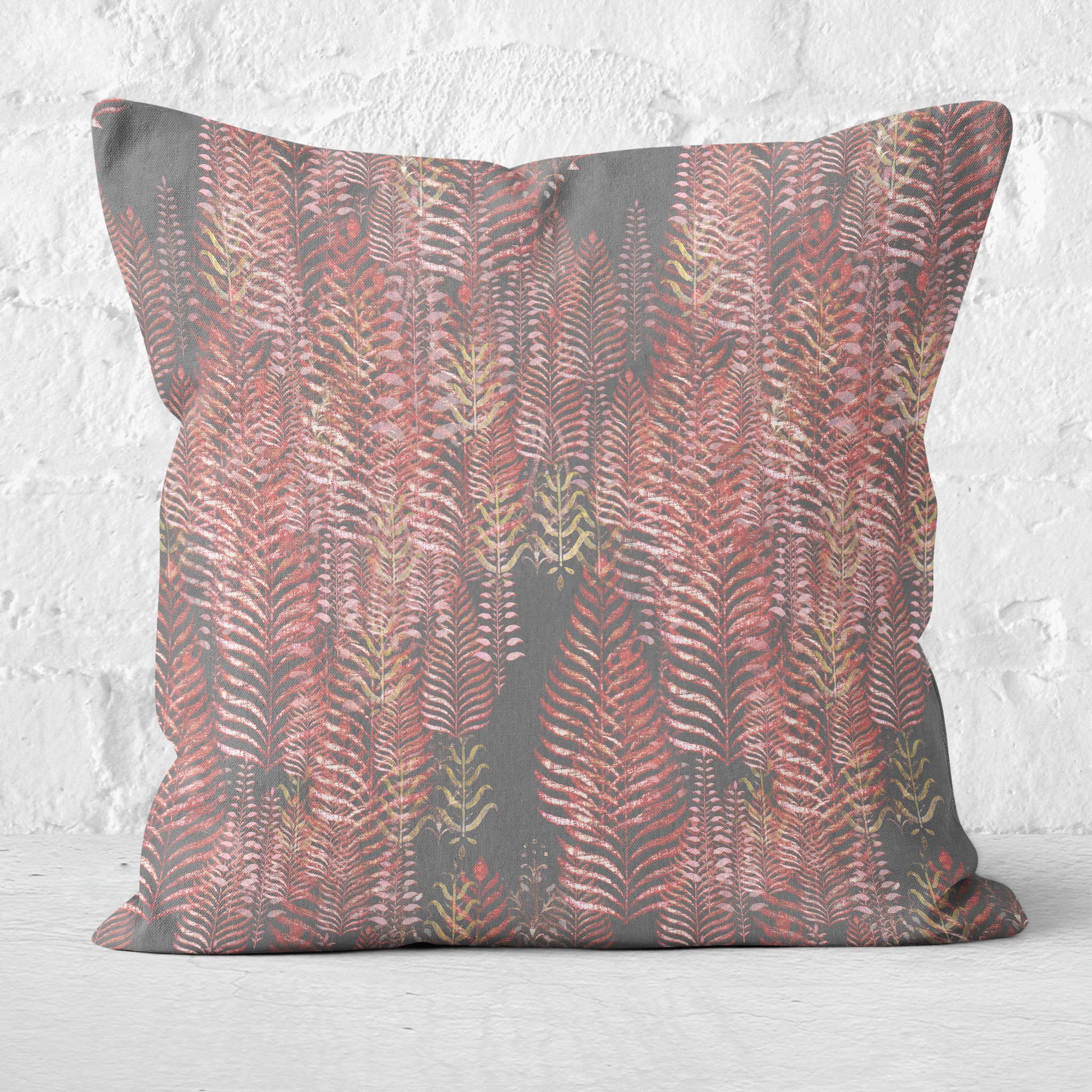 Square throw pillow set against a white brick wall, featuring a block print tree pattern in pink and gray tones.