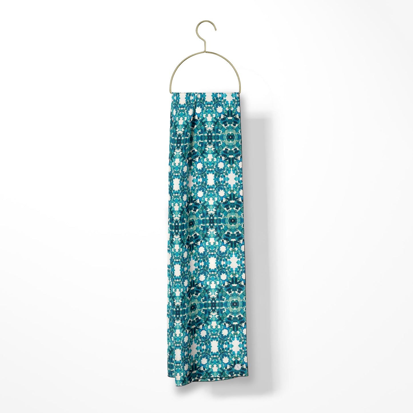 Oblong scarf featuring a teal abstract pattern and hanging from a gold hanger