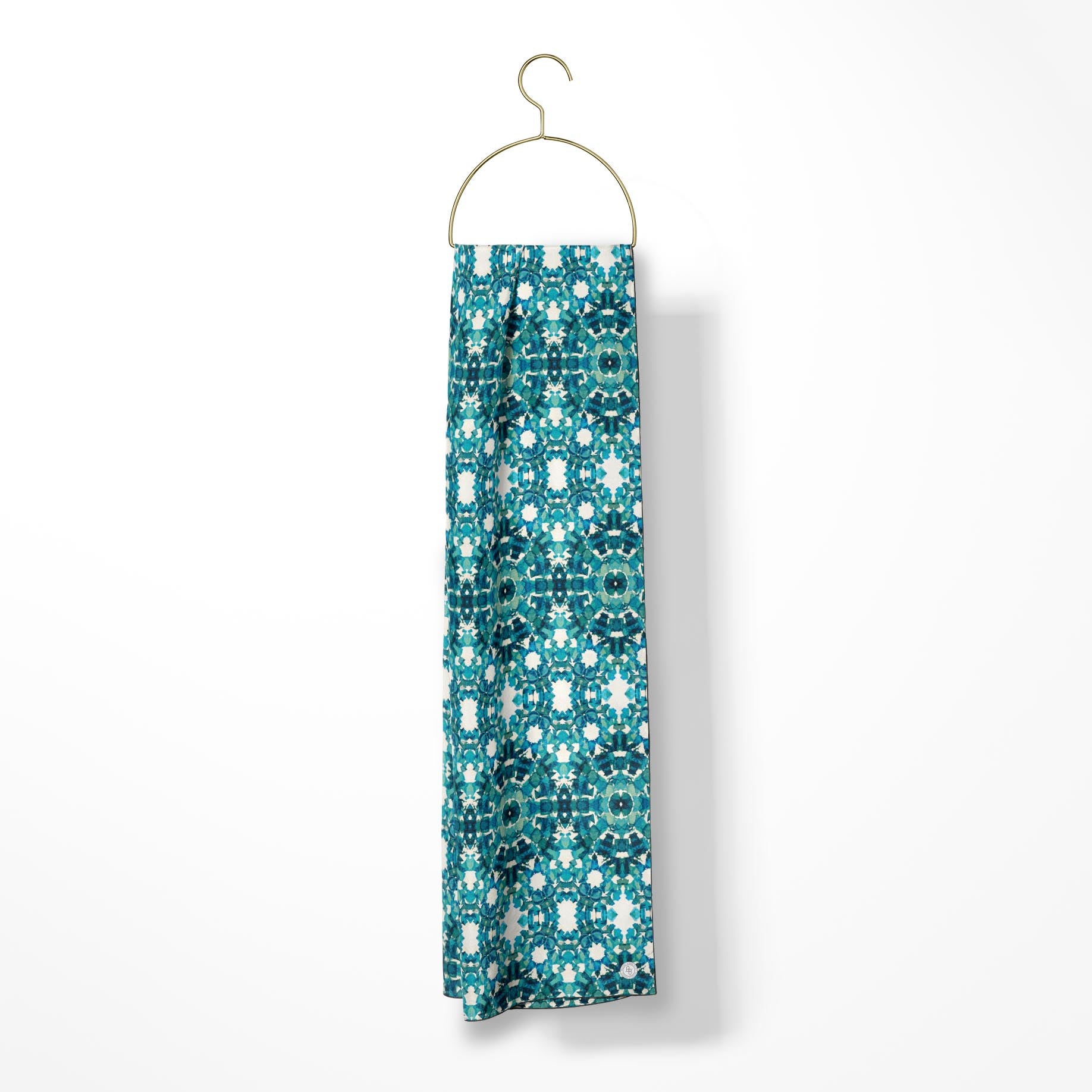 Oblong scarf featuring a teal abstract pattern and hanging from a gold hanger